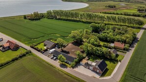 An aerial view of a residential area with houses, green fields, and a body of water.