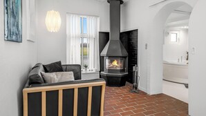 A modern living room with a fireplace, a sofa, a baby crib, and a window with blinds.
