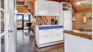 Una cocina con armarios blancos, encimera de madera y vistas al exterior.