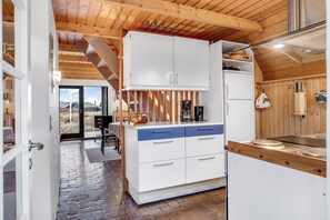Una cocina con armarios blancos, encimera de madera y vistas al exterior.