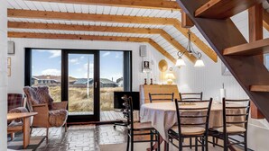 Un comedor con una mesa, sillas, televisión y vistas por un ventanal.