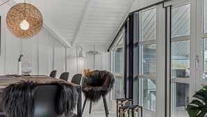 Un interior moderno con zona de comedor, un sillón de piel y un gran ventanal.