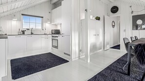 Una cocina moderna con armarios blancos, un comedor con mesa y sillas, y un ventanal grande.