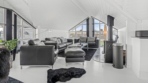 Una sala de estar moderna con chimenea, sofás de cuero negro, una mesa de centro y un ventanal grande.
