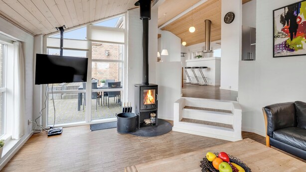 Ein modernes Wohnzimmer mit Kaminofen, Flachbildfernseher und Essbereich mit Treppe.