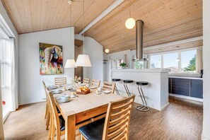 A dining area with a wooden table, chairs, and a painting on the wall. - Lovely holiday home with hot tub and sauna near Søndervig (Ringkøbing)