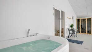 A modern bathroom with a freestanding bathtub, a shower area, and a dining area with a table and chairs.