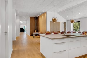 A modern kitchen with a central island, wooden accents, and pendant lighting. - Luxury pool house for 20 people with activity room and 6-person outdoor spa (Spøttrup)