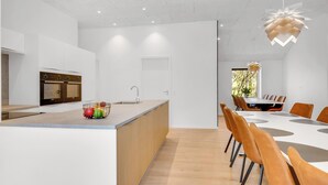 A modern kitchen with a central island, a dining area with a large table and chairs, and a view of the outdoors.