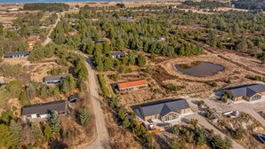 An aerial view of a residential area with houses, a pond, and a forested landscape. - Luxury holiday home with outdoor hot tub, outdoor sauna and activity room for. (Fjerritslev)