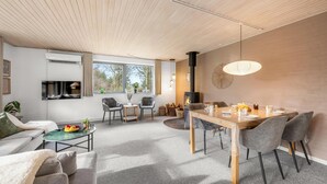 Un salon moderne comprenant un canapé, une table à manger, des chaises et une cheminée.