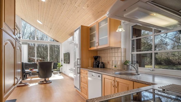 Een moderne keuken met houten kastjes, een vaatwasser, een spoelbak en een groot raam.