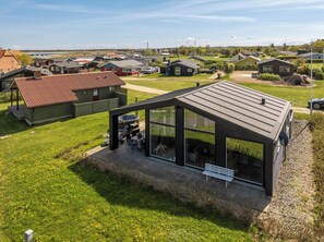 Une maison moderne dotée d’un patio, d’un jacuzzi et offrant une vue sur un quartier résidentiel.