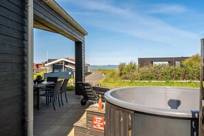 Un espace patio avec un jacuzzi, des sièges d’extérieur et une vue sur la mer.