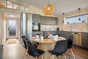 Une cuisine moderne avec un îlot central, des chaises noires et une table à manger en bois.