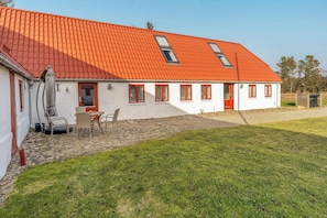 A house with a red tiled roof, white walls, and a small patio with chairs and a table.