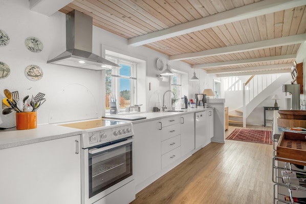 A modern kitchen with white cabinetry, a built-in oven, and a wooden ceiling.