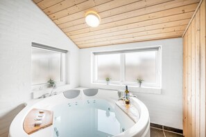 Une salle de bain moderne avec une baignoire sur pieds, un plafond en bois et de grandes fenêtres.