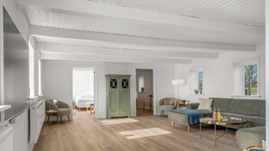 Ein geräumiges Wohnzimmer mit Holzboden, einem grünen Schrank, einem grauen Sofa und einem Couchtisch.