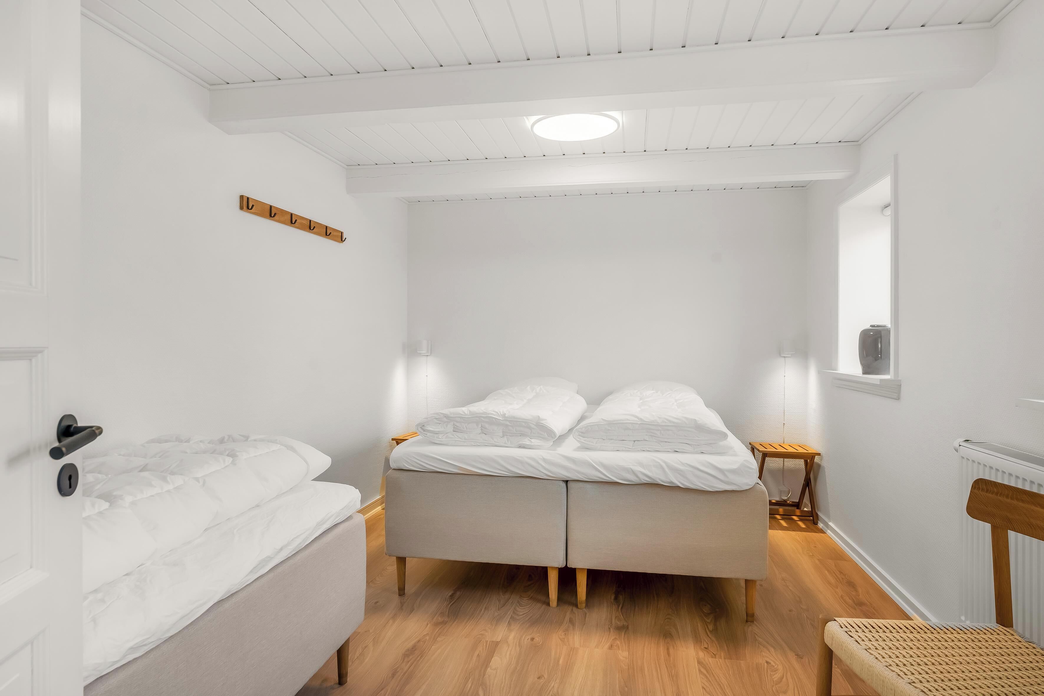 Ein Schlafzimmer mit einem Bett, Nachttischen, einem Sessel und Holzboden.
