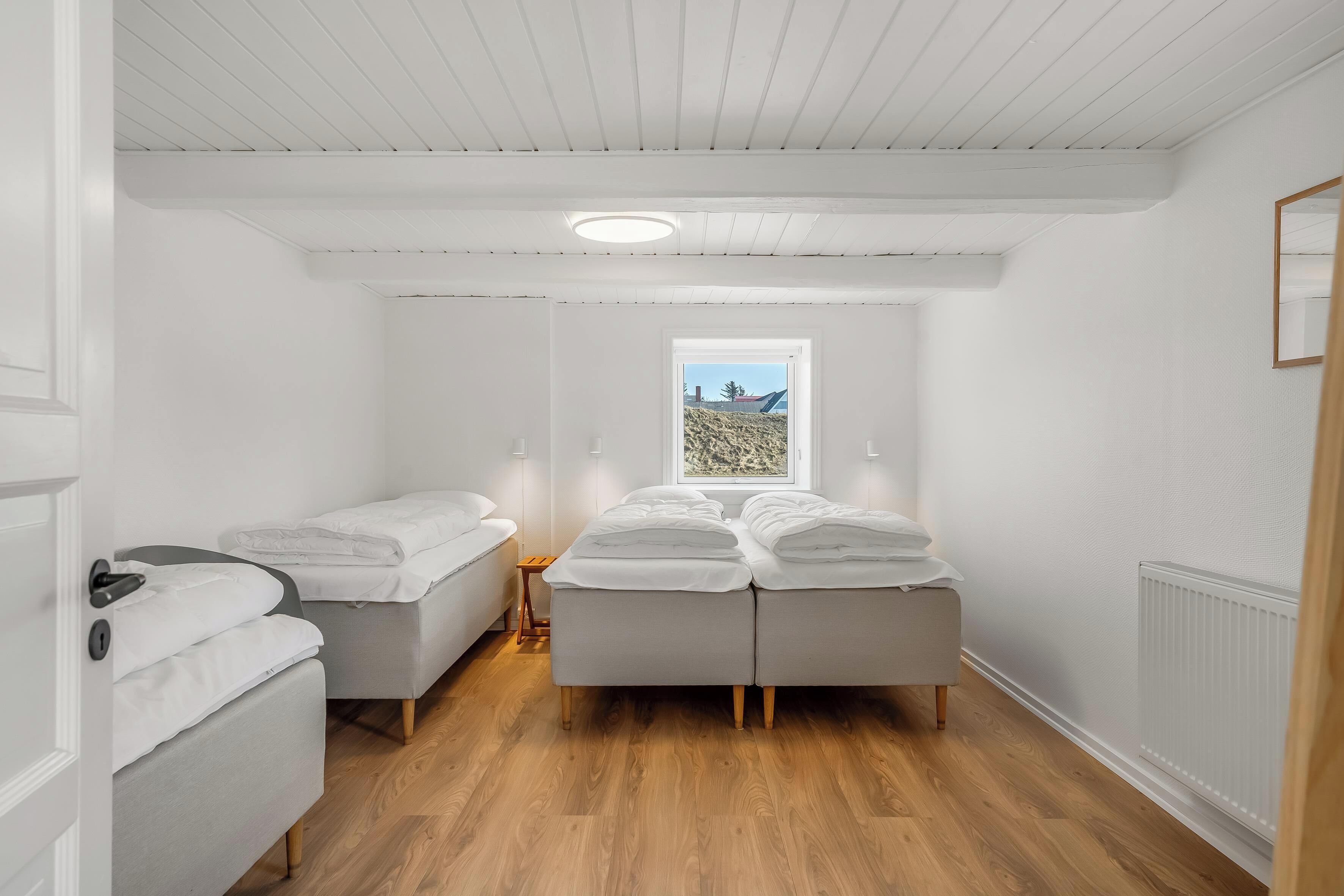 Une chambre avec un lit, deux tables de chevet, une fenêtre donnant sur un paysage agréable et un radiateur.