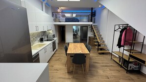 Una cocina moderna con comedor, una escalera y un perchero.