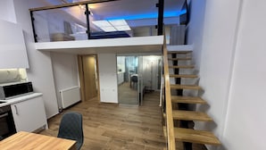 Habitación estilo loft con escalera de madera, comedor y cocina equipada con microondas.