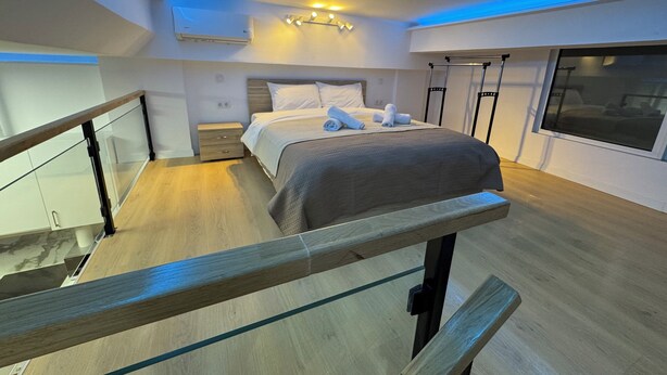 Una habitación de hotel moderna con una cama, mesita de noche y una ventana.