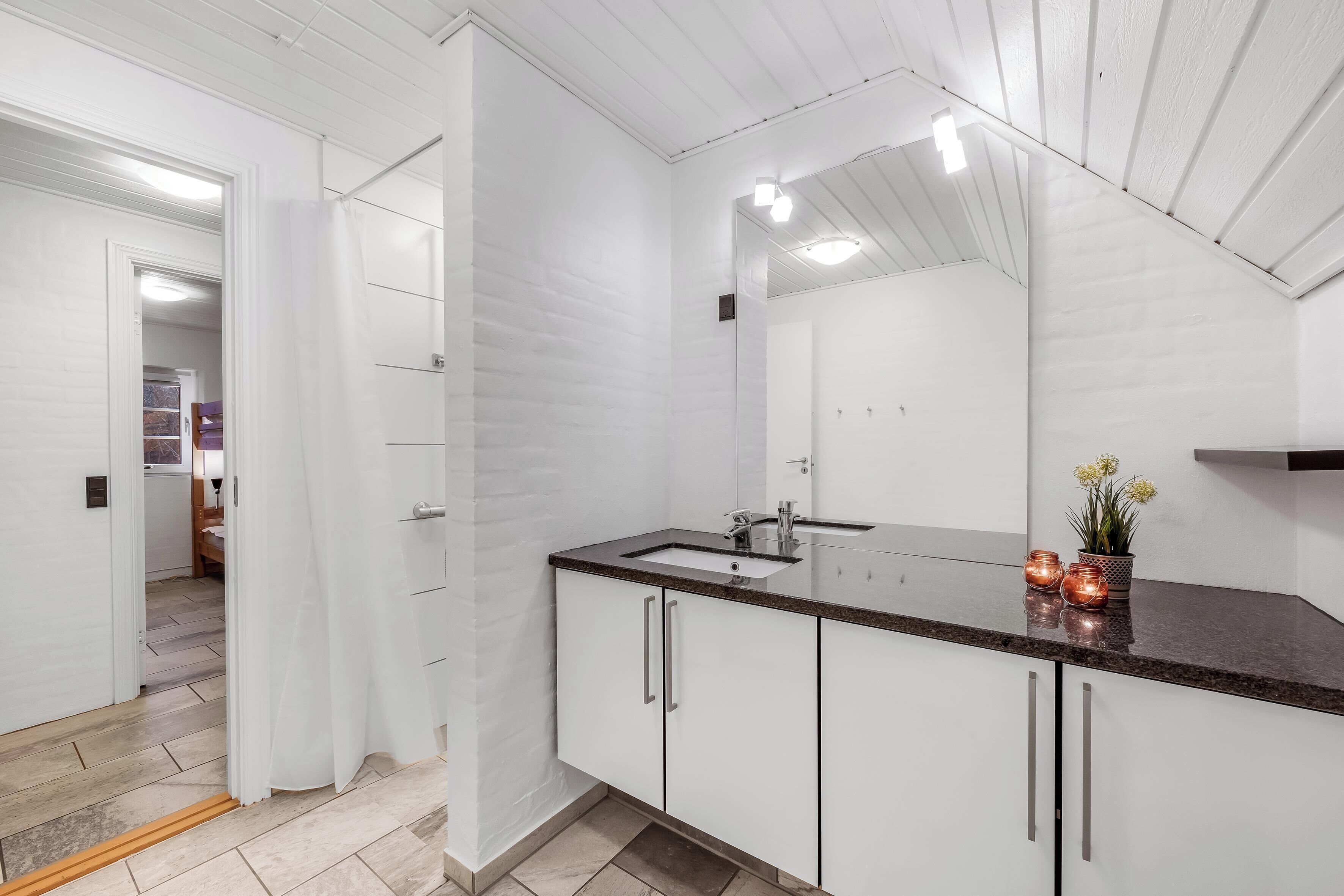 Une salle de bain moderne avec un grand miroir, des meubles blancs et un comptoir en granit.