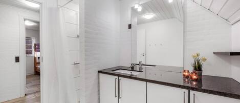 Une salle de bain moderne avec un grand miroir, des meubles blancs et un comptoir en granit.