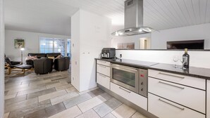 Eine moderne Küche mit Einbauofen, Edelstahlgeräten und einem großen Fenster.