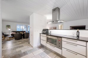 Eine moderne Küche mit Einbauofen, Edelstahlgeräten und einem großen Fenster.