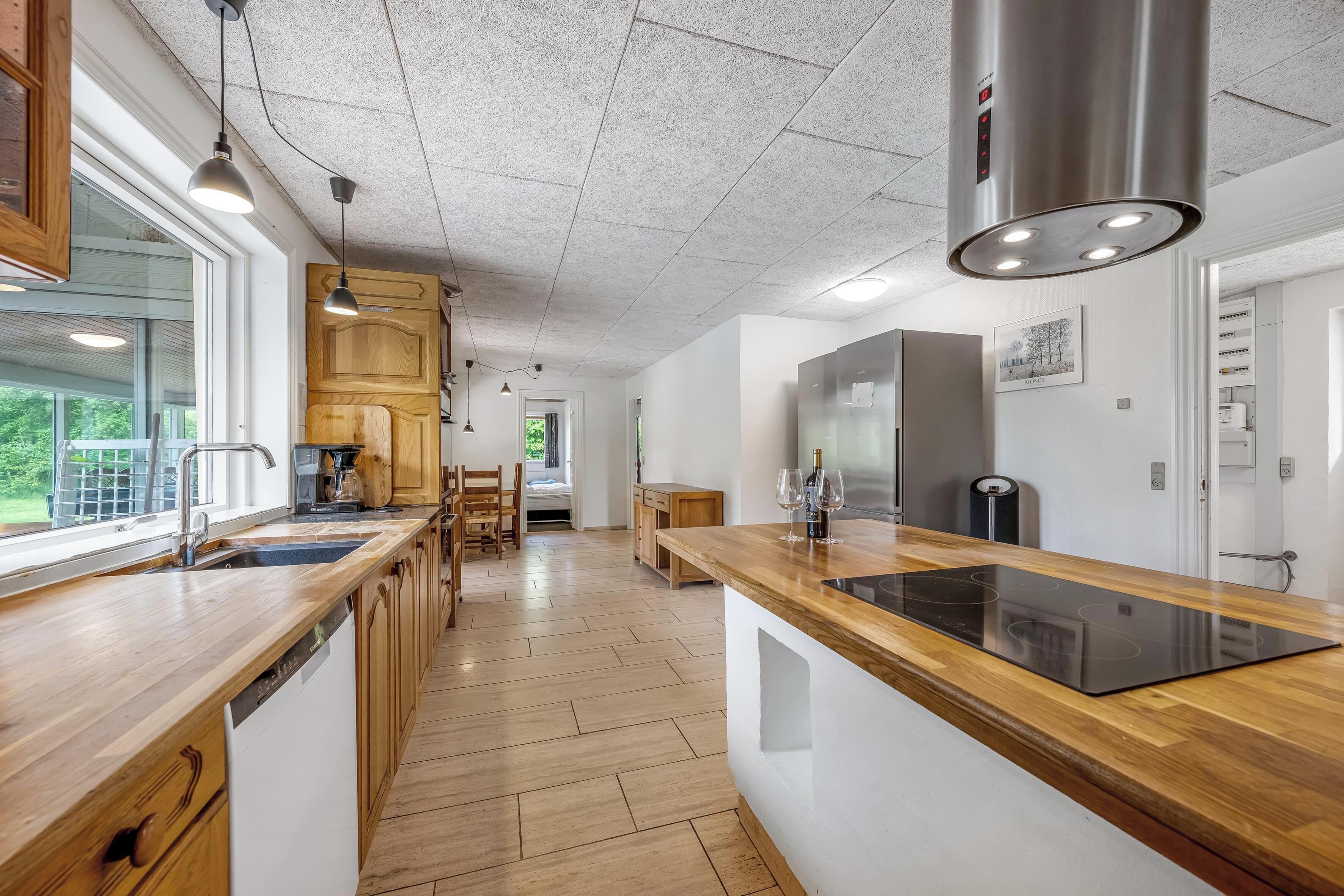 A modern kitchen with wooden cabinetry, a built-in dishwasher, and a central island with a stovetop.