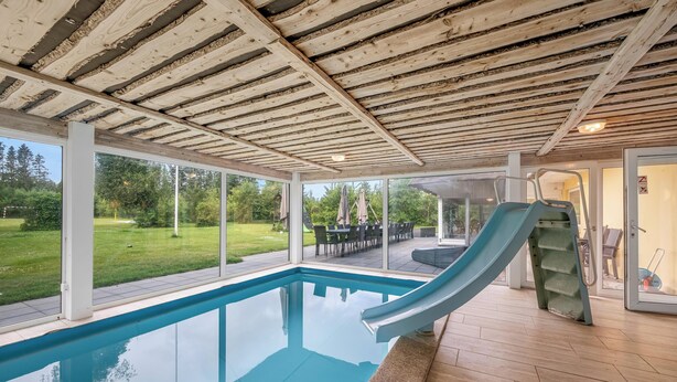 Ein Hallenbad mit Rutsche, Holzboden und großen Fenstern.