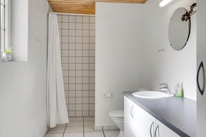 Ein Badezimmer mit Dusche, Toilette, Waschbecken und Spiegel.