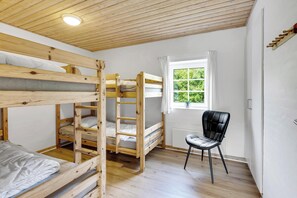 Ein Zimmer mit Etagenbetten, einem Sessel, einem Fenster mit Aussicht und einer Deckenleuchte.