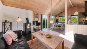 Een moderne woonkamer met een open haard, houten plafond en een eetgedeelte met natuurlijk licht.