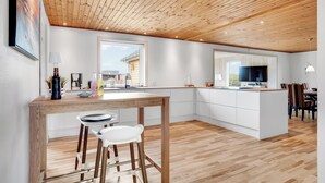 Een moderne keuken met een houten plafond, witte kasten en een centraal eiland.