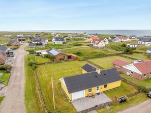 Ein Küstenwohngebiet mit Häusern, blauem Himmel und Blick auf das Meer.