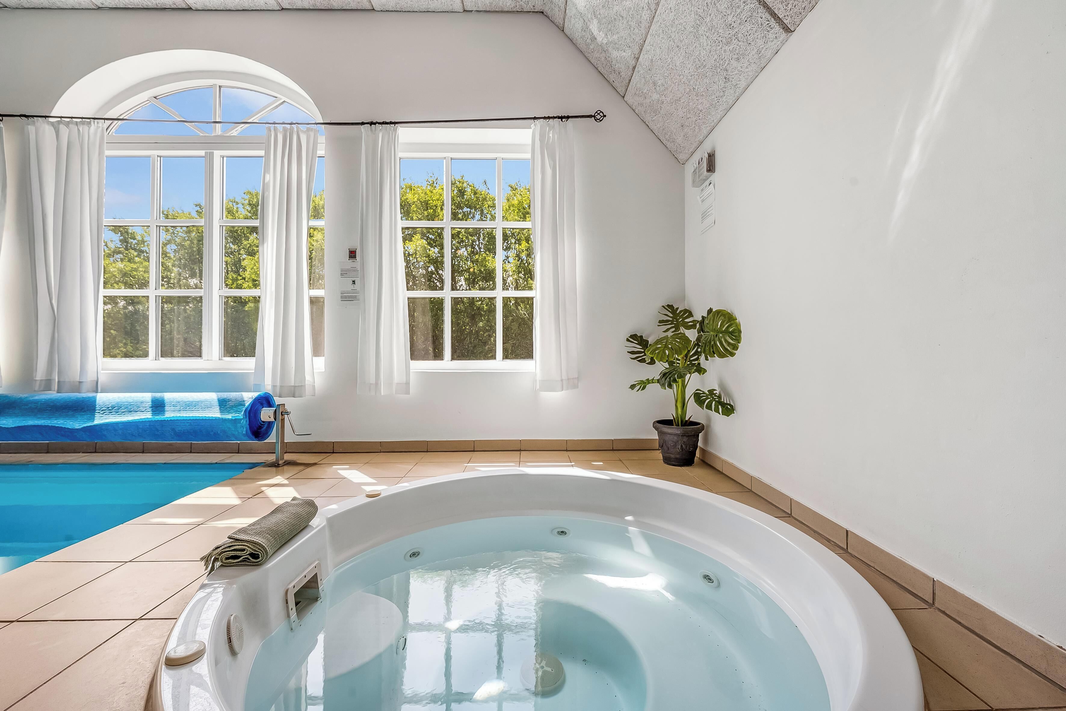 A spa area with a hot tub, a window with curtains, and a potted plant.