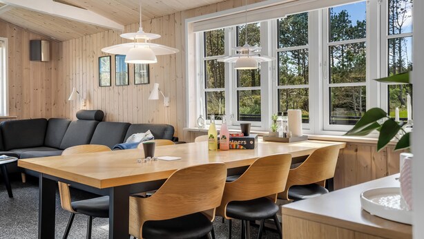 Ein modernes Interieur mit einem Holztisch, schwarzen Stühlen und einer schwarzen Couch.