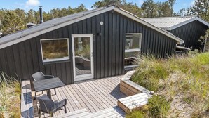 Eine Hütte mit einer Veranda, einer Schiebetür und einem Fenster.