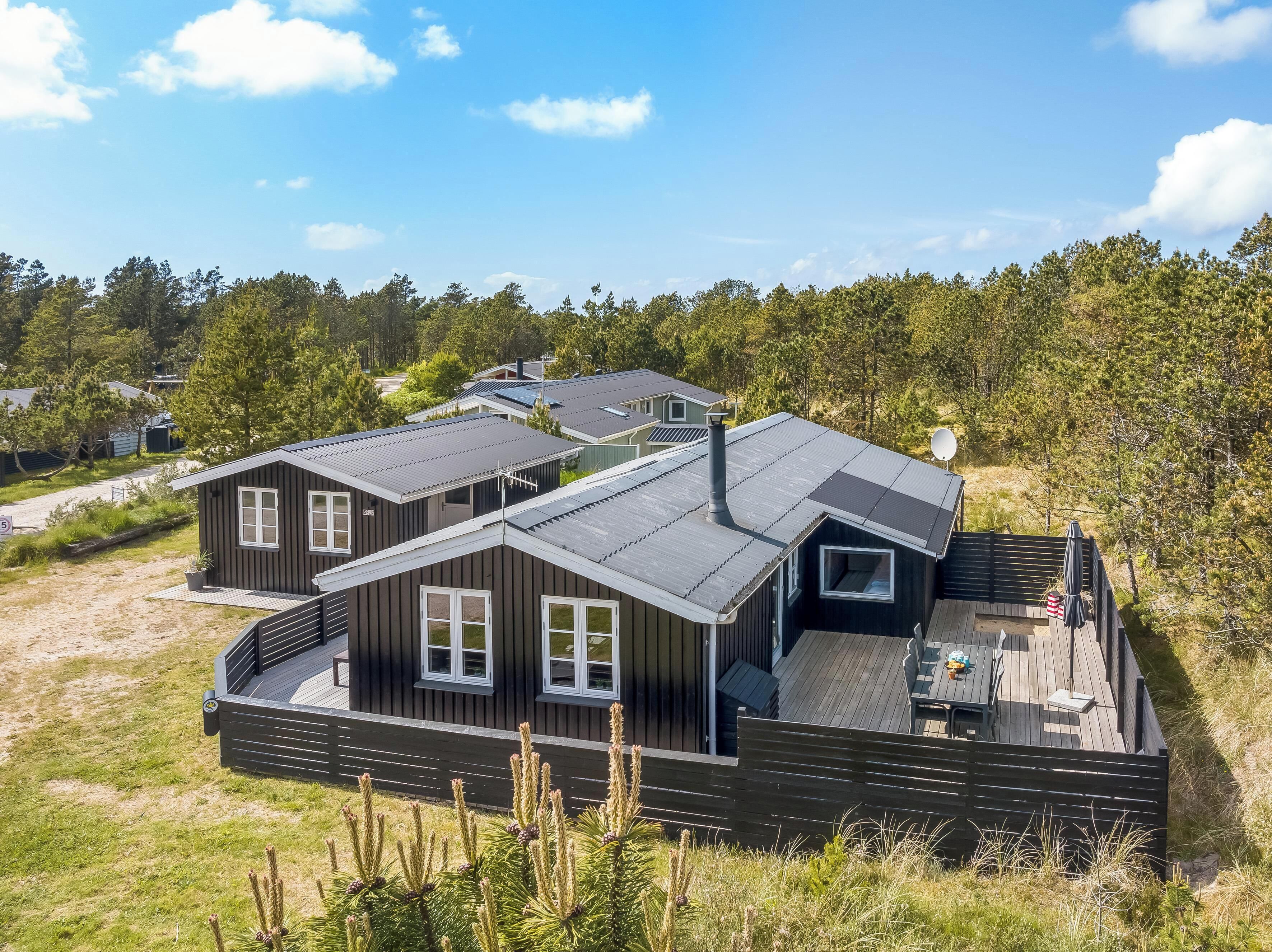 Een moderne blokhut met terras, grote ramen en een schotelantenne.