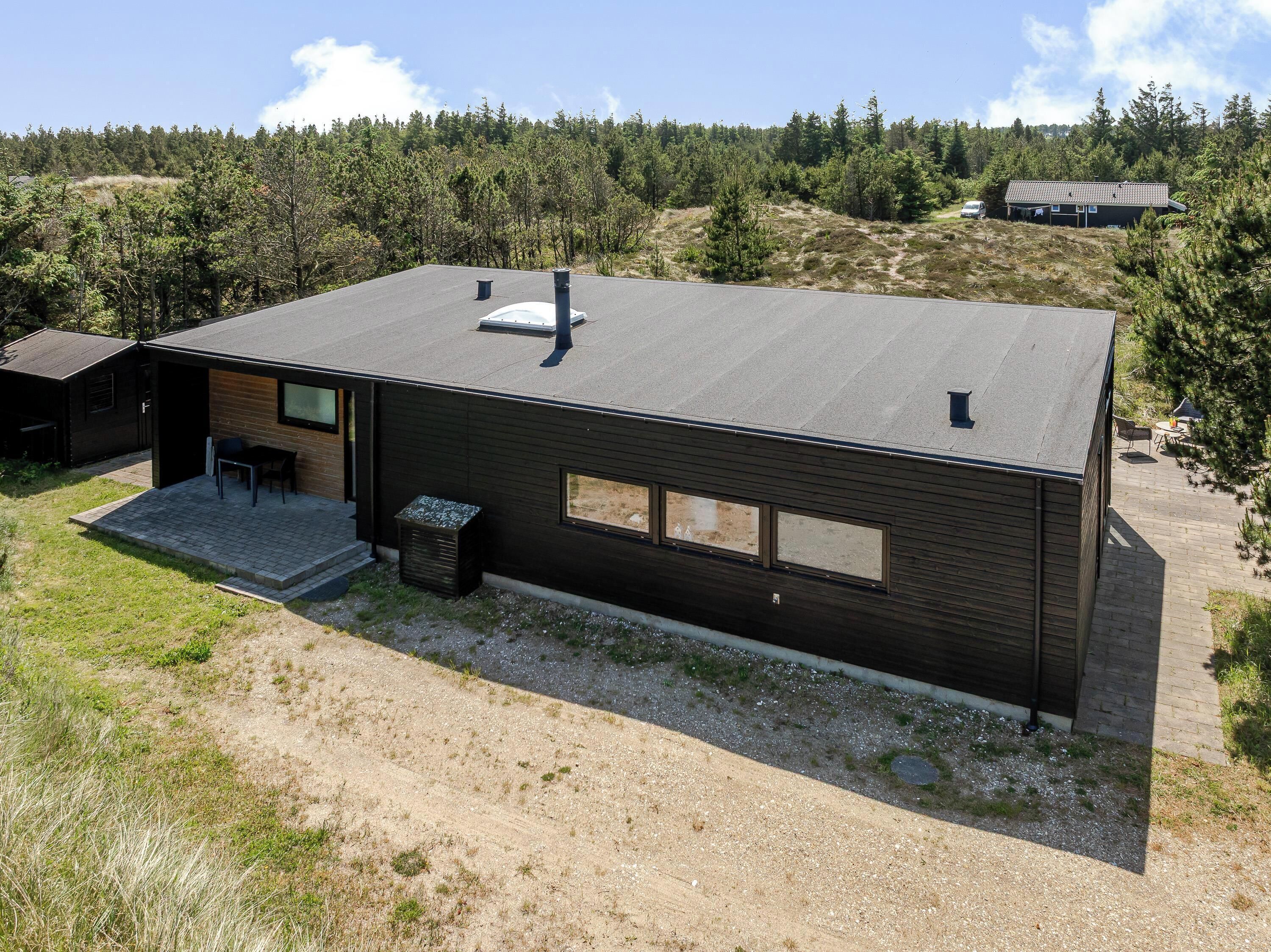 A modern, single-story building with a flat roof, large windows, and a small patio area.