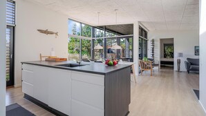 A modern kitchen with a large island, a dining area with a table and chairs, and a view of the outdoors.