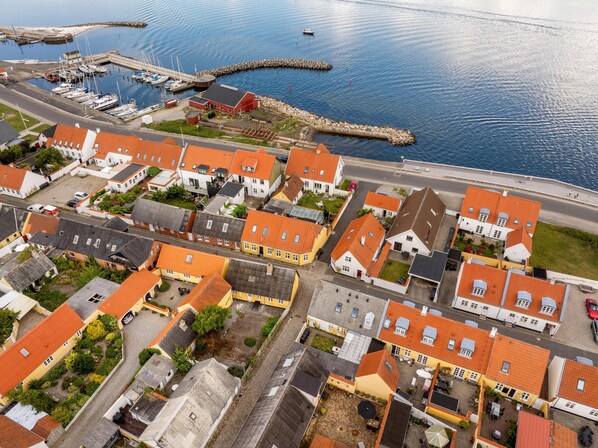 Vue aérienne d’une ville côtière avec des maisons, un port de plaisance et un quai.