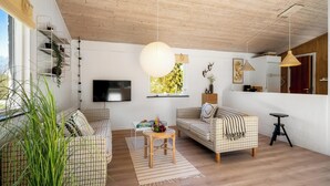 Een woonkamer met twee gestreepten banken, een televisie en een houten plafond.
