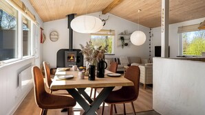 Een eetruimte met een houten tafel, bruine stoelen en een open haard.