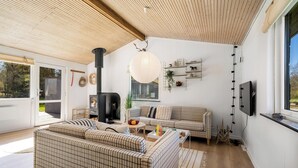 Een moderne woonkamer met een grote bank, een open haard, een televisie en een groot raam.