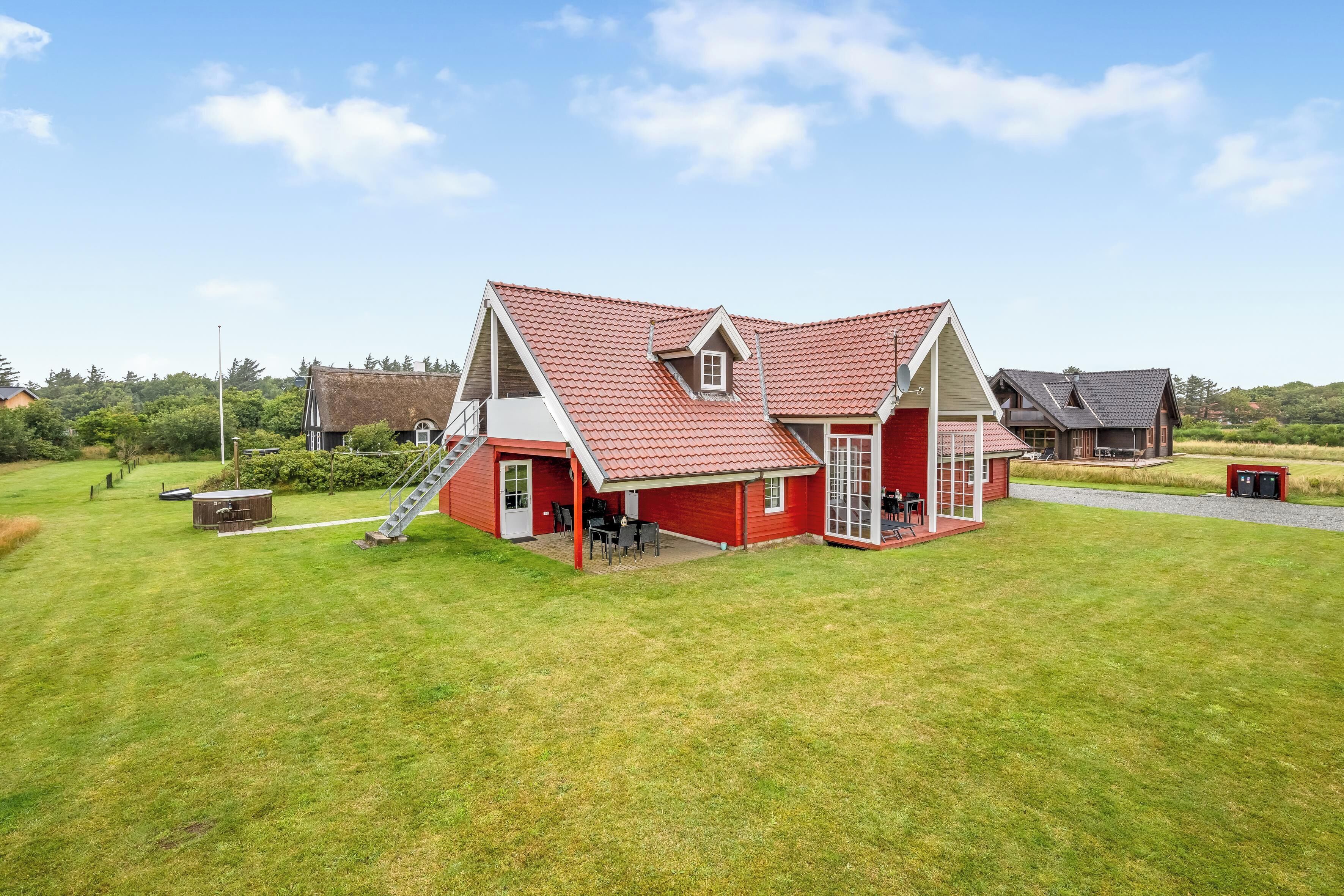 A red-roofed house with a covered patio, a small attached shed, and a grassy yard.